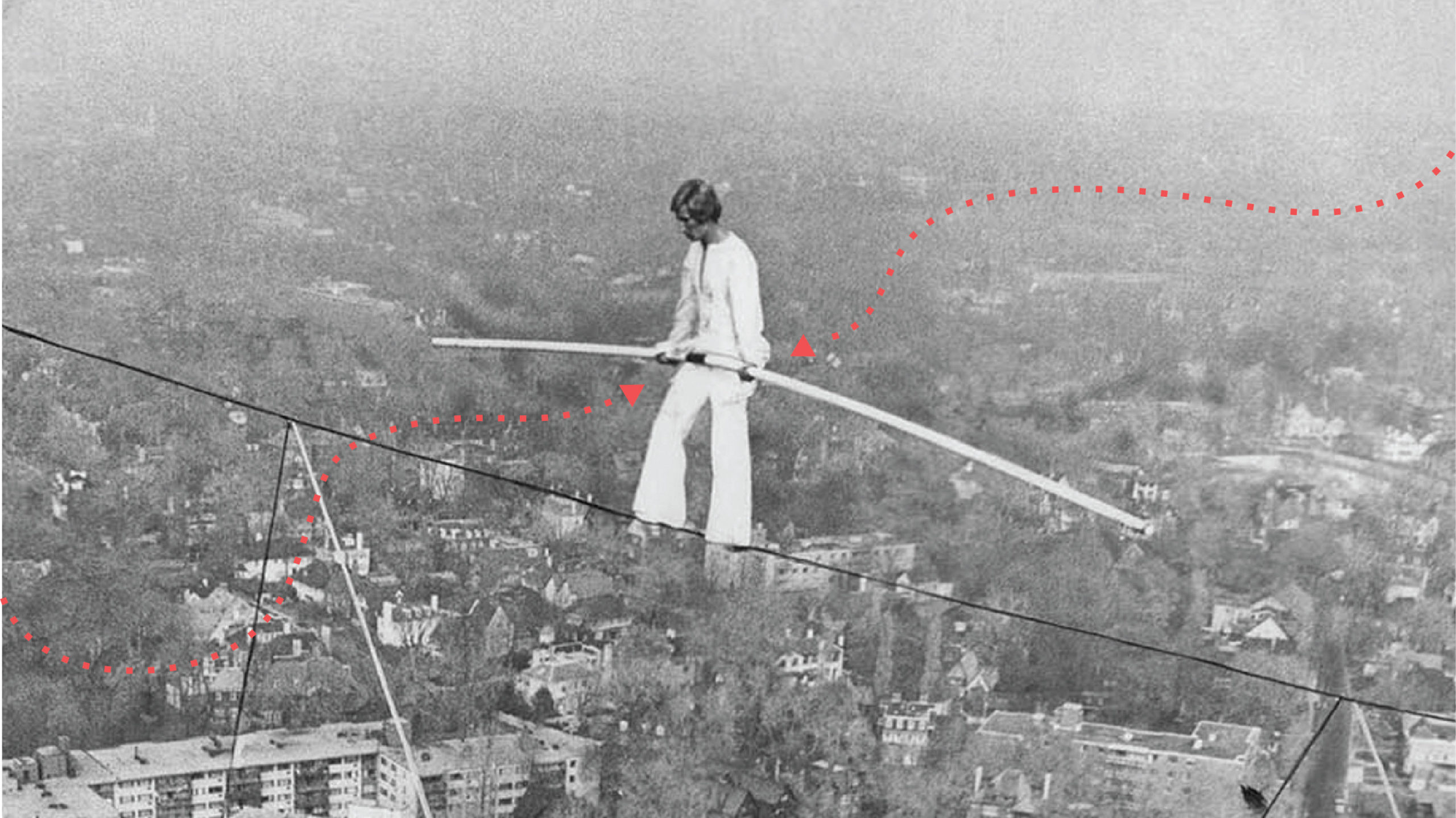 a man walking as tightrope high above a city